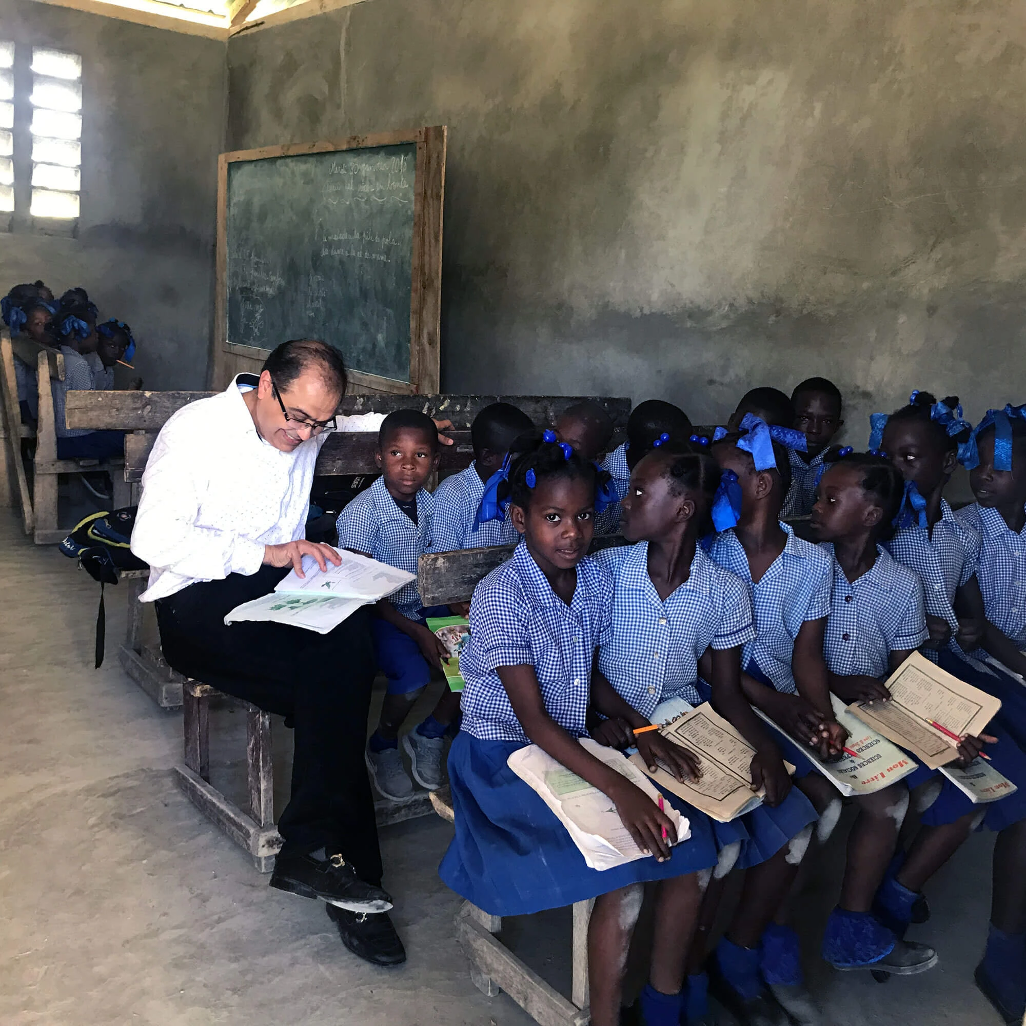 Puneet Nanda reading with schoolchildren in blue uniforms in a classroom