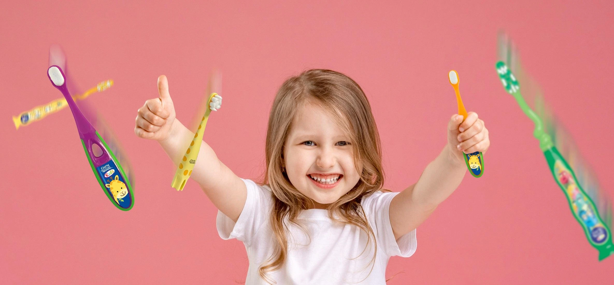 A laughing girl with her arms up, GuruNanda kids toothbrushes flying around her