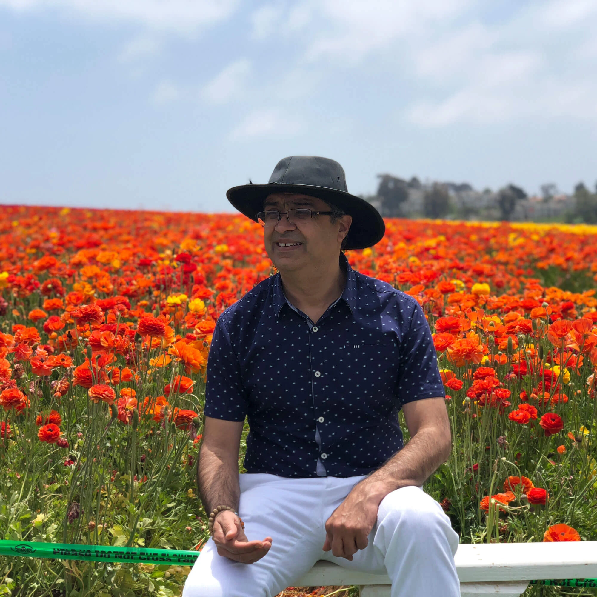 Puneet Nanda sitting in a field of orange and red flowers